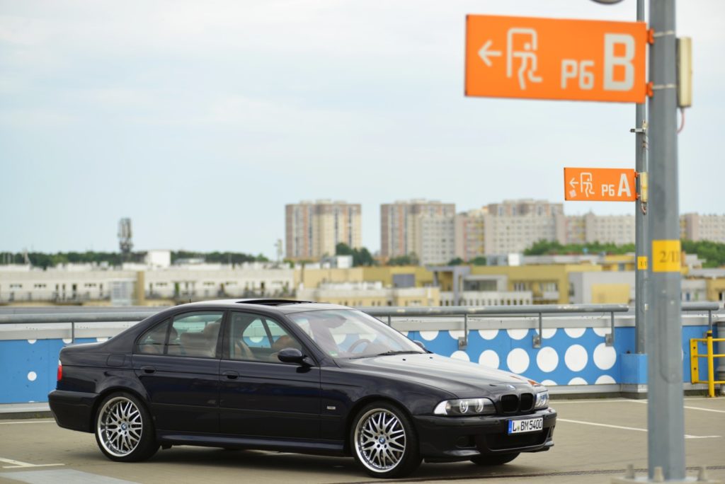 Zdjęcie kolekcjonerskiego BMW E39 M5 INDIVIDUAL w kolorze czarnym z profilu na tle miasta