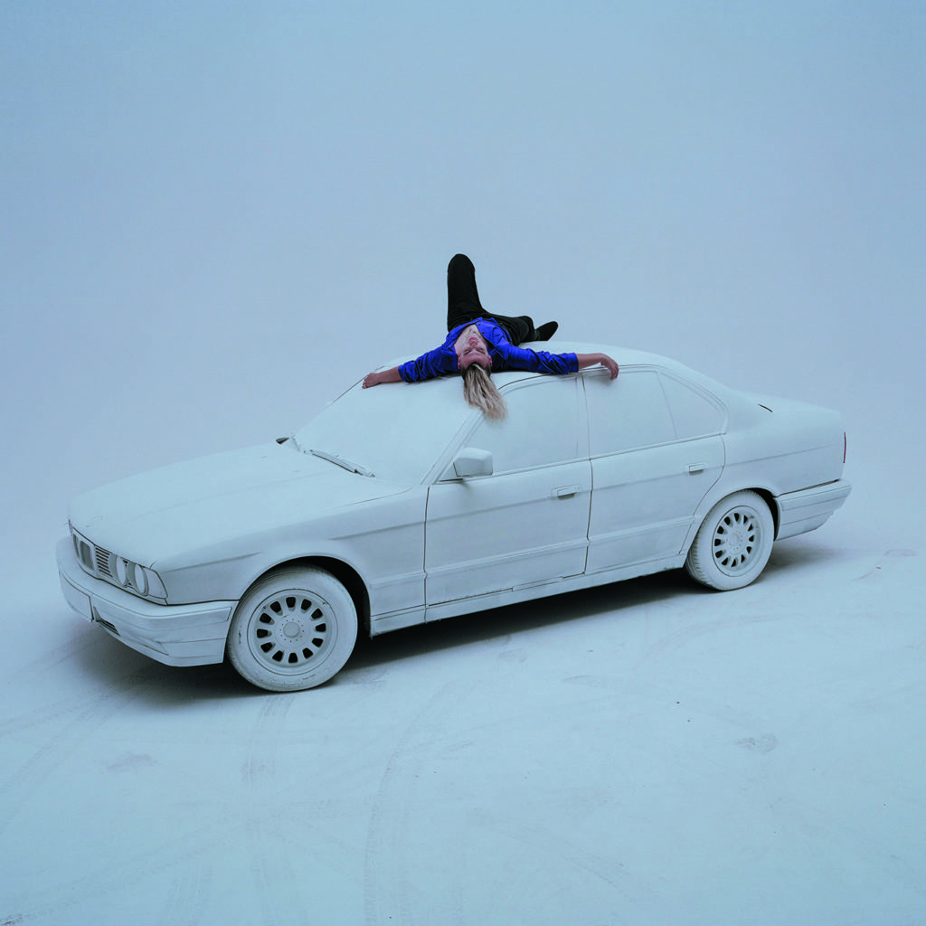 Okładka płyty White 2115 Rockstar przedstawiająca rapera leżącego na samochodzie