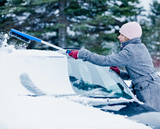 Kobieta usuwa śnieg z auta