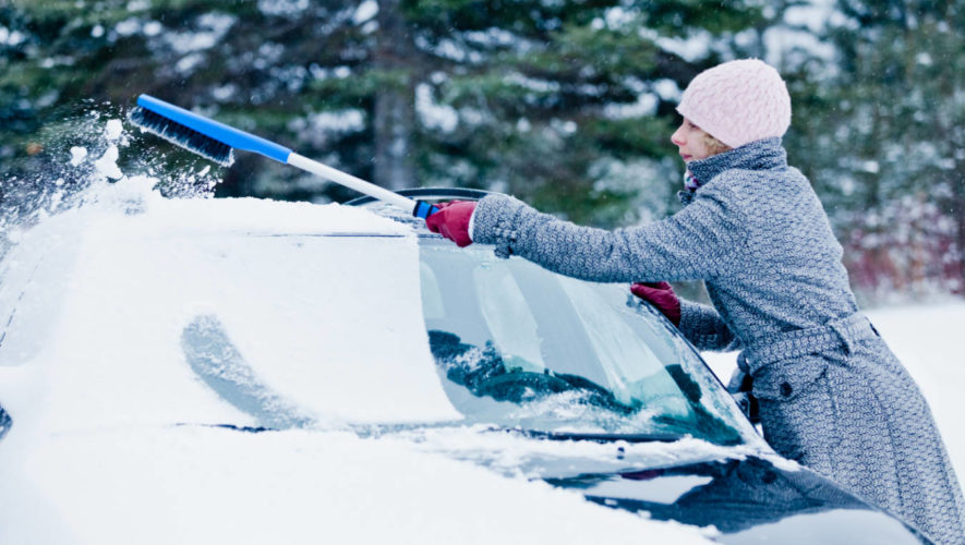 Kobieta usuwa śnieg z auta