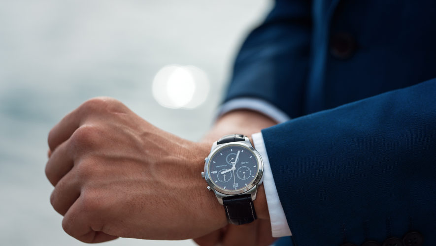 A man in a business suit checking a wrist watch on his hand on background sea
