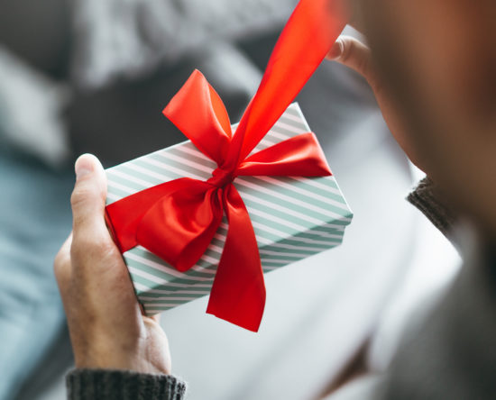 Man holding gift with red ribbon